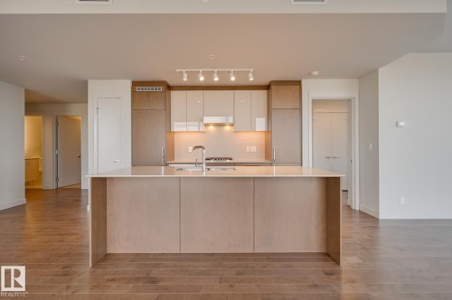 Modern kitchen island with an integrated sink and light countertop - #3901 10360 102 St Nw Nw, Edmonton, AB - Indoor Photo Showing Kitchen