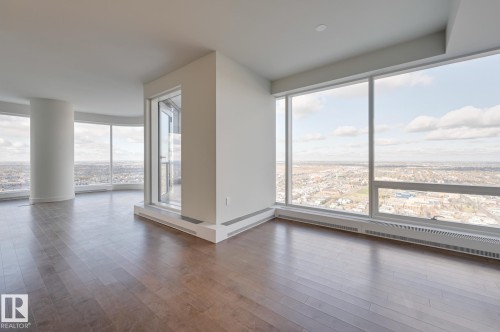 Expansive interior featuring wood-finish flooring, a curved architectural column, and floor-to-ceiling windows - #3901 10360 102 St Nw Nw, Edmonton, AB - Indoor