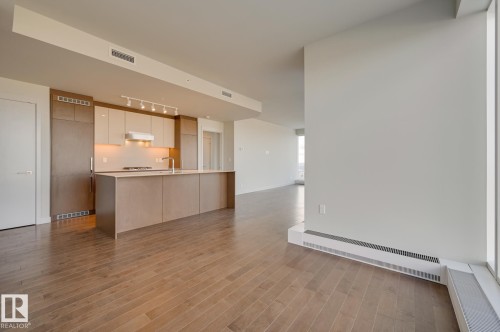 Contemporary kitchen featuring a large island, integrated appliances, track lighting, light wood-finish flooring, and expansive windows providing abundant natural light - #3901 10360 102 St Nw Nw, Edmonton, AB - Indoor Photo Showing Kitchen