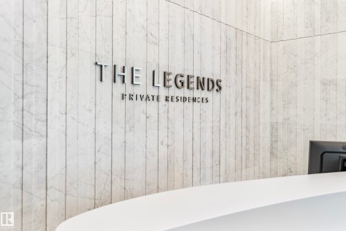 Lobby entrance featuring a white marble wall with vertical paneling, contemporary signage with raised lettering, and a white curved reception desk - #3901 10360 102 St Nw Nw, Edmonton, AB - Indoor Photo Showing Bathroom