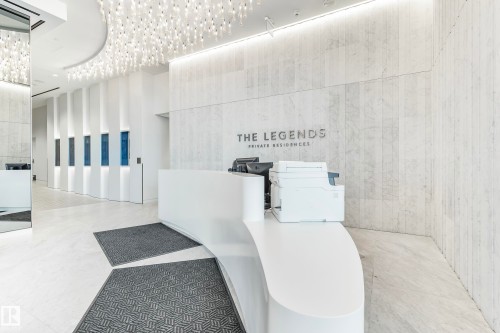 Contemporary lobby featuring a curved reception desk, large format tile flooring, and a decorative ceiling light fixture - #3901 10360 102 St Nw Nw, Edmonton, AB - Indoor Photo Showing Other Room