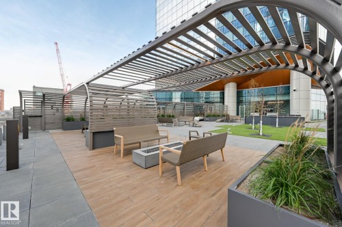 Rooftop patio featuring wood-finish flooring, paver stone pathways, a slatted pergola, and integrated planters - #3901 10360 102 St Nw Nw, Edmonton, AB - Outdoor