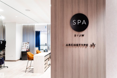 Wood-finish wall paneling featuring a black circular "SPA" sign - #3901 10360 102 St Nw Nw, Edmonton, AB - Indoor