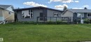 Contemporary-style residence featuring grey horizontal siding and a prominent stone facade accent - 10523 105 Street, Westlock, AB 