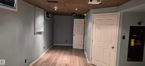 Room featuring wood-finish flooring, light blue walls, and multiple paneled doors - 10523 105 Street, Westlock, AB 