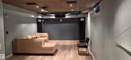 Entertainment room featuring recessed lighting, a ceiling-mounted projector, wood-finish flooring, and a sound-absorbing ceiling - 10523 105 Street, Westlock, AB 