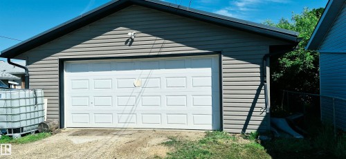 Two-car garage featuring a white panel door, gray siding, and dark trim - 10523 105 Street, Westlock, AB 