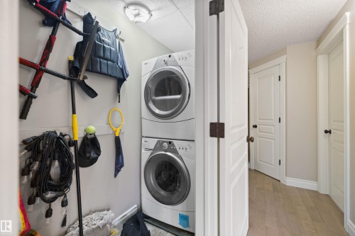 Dedicated laundry area featuring a stacked washer and dryer, light gray walls, and a textured ceiling - #206 10232 115 St Nw, Edmonton, AB 
