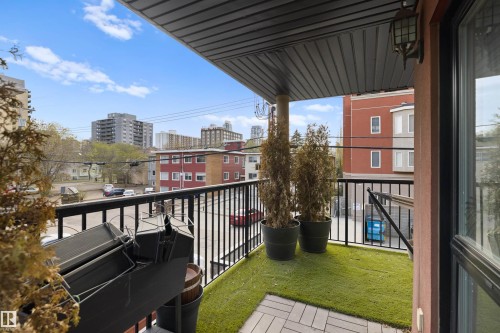 Balcony with dark metal railing, artificial turf flooring, and paver accents - #206 10232 115 St Nw, Edmonton, AB 