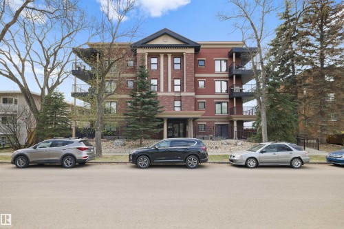 Multi-story residential building featuring brick facade, prominent architectural columns, multiple balconies, and mature landscaping - #206 10232 115 St Nw, Edmonton, AB 