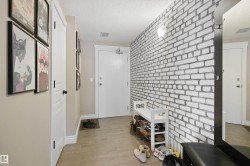 Entryway featuring a white brick-pattern accent wall, neutral-toned walls, and wood-finish flooring - 