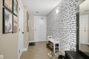 Entryway featuring a white brick-pattern accent wall, neutral-toned walls, and wood-finish flooring - #206 10232 115 St Nw, Edmonton, AB 