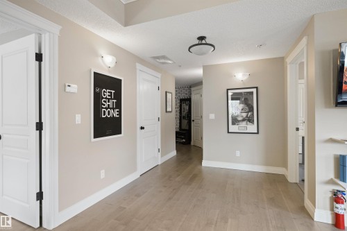 Spacious hallway featuring light wood-finish flooring, neutral wall paint, and white trim - #206 10232 115 St Nw, Edmonton, AB 