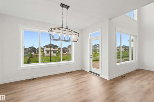 Spacious interior featuring wood-finish flooring, white walls, and a contemporary linear chandelier - 2232 5 Avenue, Edmonton, AB 