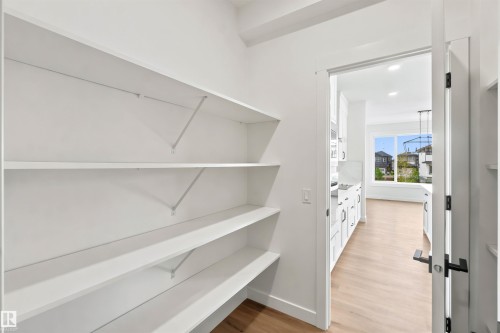 Walk-in pantry featuring multiple levels of white shelving, wood-finish flooring, and white baseboards - 2232 5 Avenue, Edmonton, AB 