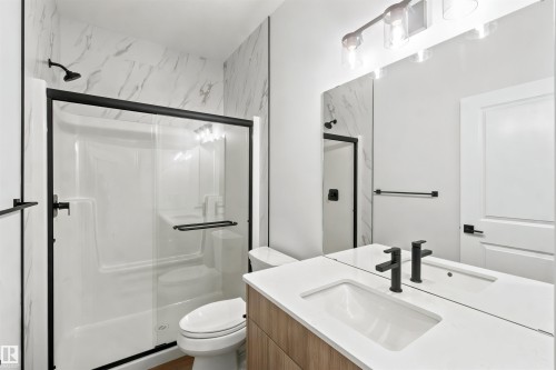 Full bathroom featuring a shower-tub combination with a sliding glass door, a single vanity with an integrated sink and white countertop, and wood-finish cabinetry - 2232 5 Avenue, Edmonton, AB 
