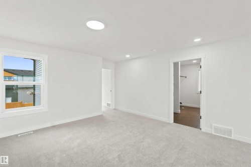 Spacious room featuring light-colored carpeting, a double-hung window, and a circular ceiling light fixture - 2232 5 Avenue, Edmonton, AB 