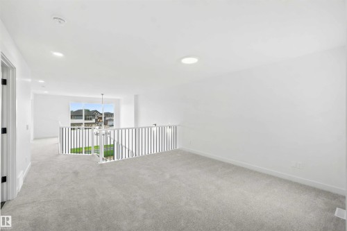 Upper-level landing featuring light gray carpeting, white walls, and a white railing with vertical balusters - 2232 5 Avenue, Edmonton, AB 