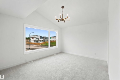 Spacious interior room with vaulted ceilings, large windows, light grey carpet, and a modern ceiling light fixture - 2232 5 Avenue, Edmonton, AB 