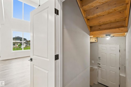 Two-story room featuring multiple windows with transoms, light wood-finish flooring, and a white paneled door with dark hardware - 2232 5 Avenue, Edmonton, AB 