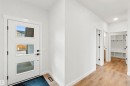 Entryway featuring a contemporary white door with three rectangular lites, a light wood-finish floor, and bright white walls - 2232 5 Avenue, Edmonton, AB 