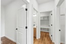Hallway with wood-finish flooring, white paneled doors, and matte black hardware - 2232 5 Avenue, Edmonton, AB 