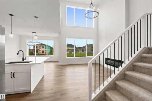 Two-story entry with an open staircase featuring carpeted treads and black metal balusters - 2232 5 Avenue, Edmonton, AB 