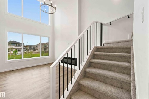 Two-story entry featuring light wood-finish flooring and a contemporary chandelier - 2232 5 Avenue, Edmonton, AB 