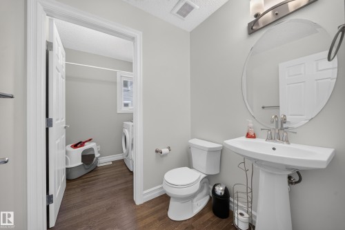 Pedestal sink with a wall-mounted oval mirror and overhead vanity lighting - 64 655 Tamarack Road, Edmonton, AB 