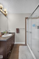 Bathroom featuring a dark wood vanity with a stone-look countertop, an undermount sink, and a mirrored wall - 