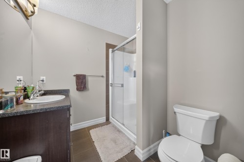 Bathroom featuring a single vanity with dark cabinetry, an undermount sink, and a speckled countertop - 64 655 Tamarack Road, Edmonton, AB 