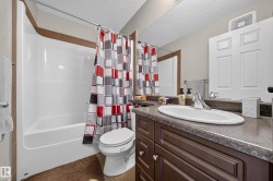 Bathroom featuring a white tub/shower combination, a dark wood-finish vanity with a countertop, an oval undermount sink, and a chrome faucet - 