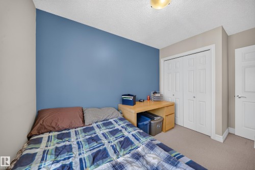 Interior room featuring a bold accent wall, neutral carpeting, and a built-in light wood-finish desk - 64 655 Tamarack Road, Edmonton, AB 