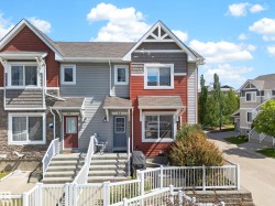 Townhome exterior featuring multi-toned siding, stone veneer accents, and a prominent gable roofline with decorative truss detailing - 