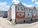 Contemporary multi-level townhome featuring a mixed-material facade with red and grey horizontal siding - 64 655 Tamarack Road, Edmonton, AB 