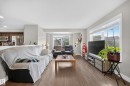 Open-concept living area featuring wood-finish flooring and ample natural light from large windows - 64 655 Tamarack Road, Edmonton, AB 