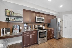 Kitchen featuring wood-finish flooring, dark wood cabinetry, and stainless steel appliances - 