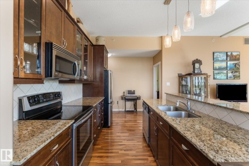 Kitchen featuring wood-finish flooring, dark wood cabinetry, and light-colored countertops - 408 11140 68 Avenue, Edmonton, AB 