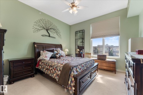 Spacious room featuring a ceiling fan, broad window with an exterior outlook, and neutral carpeting - 408 11140 68 Avenue, Edmonton, AB 