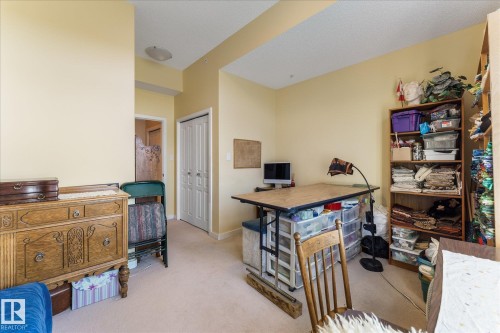 Carpeted interior room featuring warm-toned walls, white trim, and a ceiling-mounted light fixture - 408 11140 68 Avenue, Edmonton, AB 
