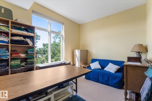 Spacious room featuring floor-to-ceiling windows, soft wall-to-wall carpeting, and a built-in shelving unit - 408 11140 68 Avenue, Edmonton, AB 
