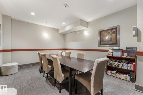 Spacious room featuring recessed lighting, wall sconces, a dropped ceiling detail, and a built-in wood-finish shelving unit - 408 11140 68 Avenue, Edmonton, AB 