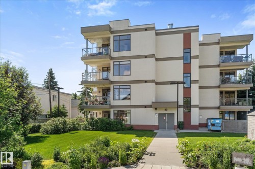 Multi-story residential building featuring a light-toned facade with contrasting vertical red accents - 408 11140 68 Avenue, Edmonton, AB 