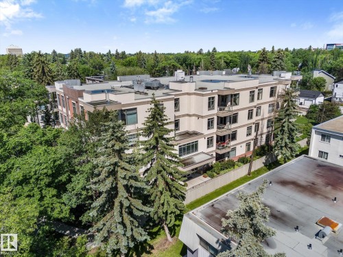 Multi-story residential building with a flat roof, featuring a cream-colored facade with dark trim windows and multiple balconies - 408 11140 68 Avenue, Edmonton, AB 