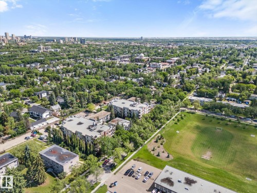 Expansive aerial perspective showcasing a residential area with a prominent green field, multi-story buildings, and a dense tree canopy - 408 11140 68 Avenue, Edmonton, AB 