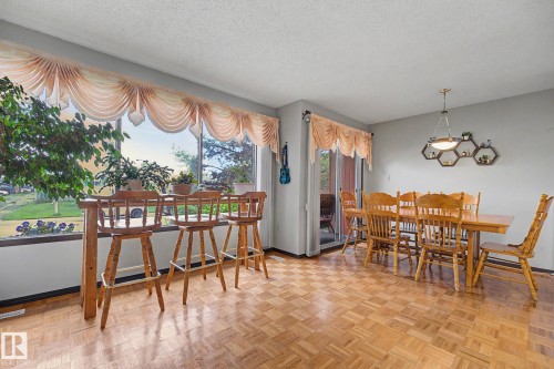 Expansive window with a built-in bar table, parquet wood-finish flooring, a sliding glass door, and a geometric wall-mounted shelving unit - 10242 161 Street, Edmonton, AB 
