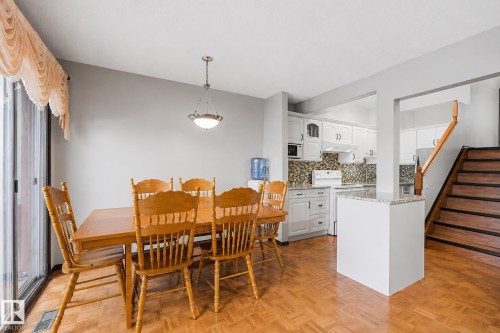 Open-concept dining area featuring wood-finish parquet flooring and a sliding glass door - 10242 161 Street, Edmonton, AB 