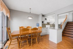 Open-concept dining area featuring wood-finish parquet flooring and a sliding glass door - 