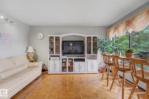 Parquet wood-finish flooring throughout, complemented by a large picture window with drapes, and a built-in media center - 10242 161 Street, Edmonton, AB 