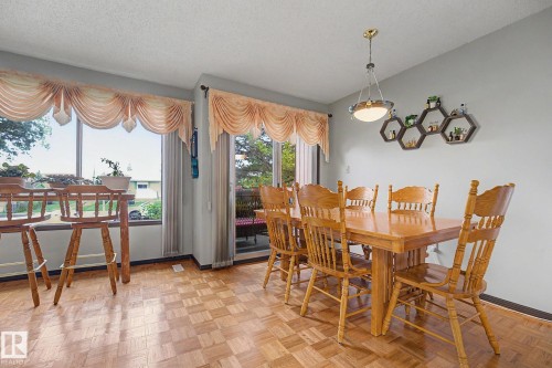 Dining area featuring a parquet wood-finish floor, a large window, and a glass-paneled sliding door - 10242 161 Street, Edmonton, AB 